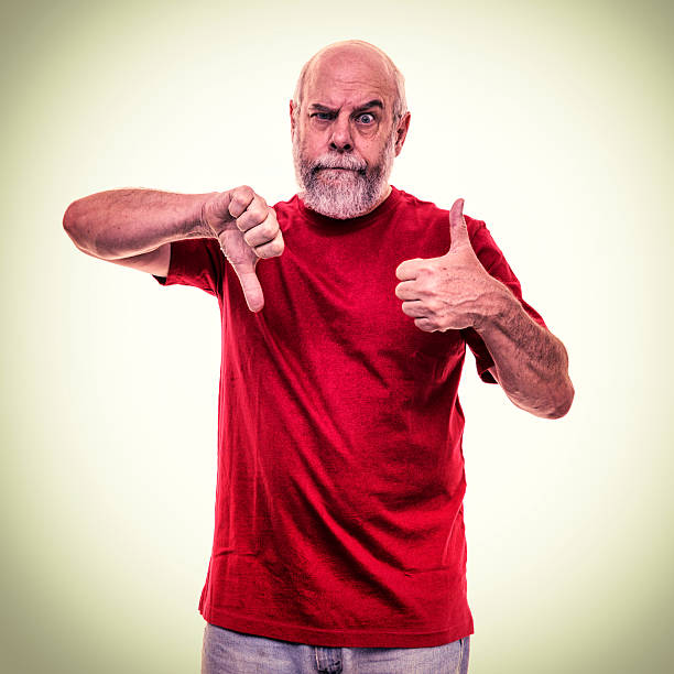 istock Frustrated Red Shirt Senior Man Conflicting Thumbs Up Down Gestures 620718800
