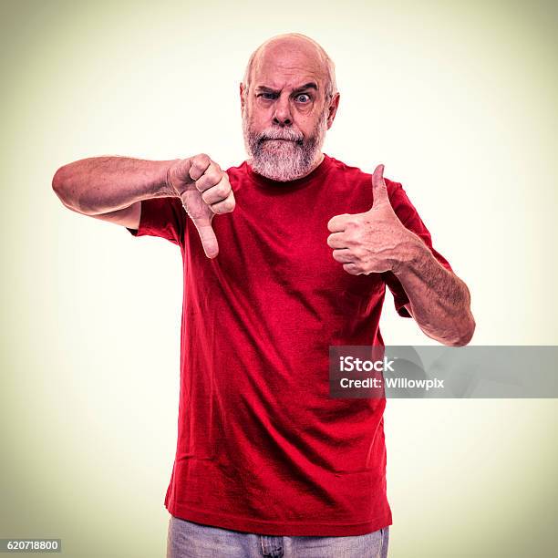 Frustrated Red Shirt Senior Man Conflicting Thumbs Up Down Gestures Stock Photo - Download Image Now