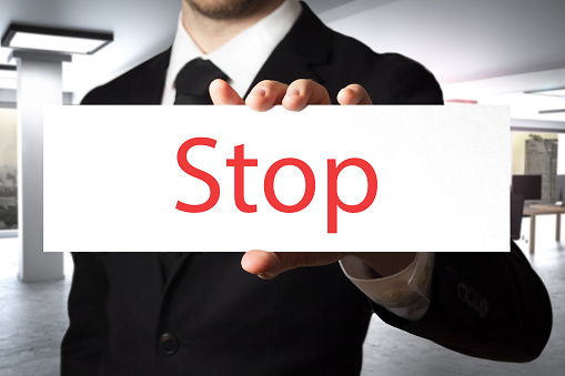 businessman in black suit showing sign stop