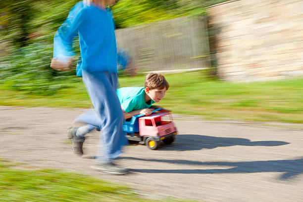 istock Two Boys Riding Downhill on Top of Toy Lorry 620727402