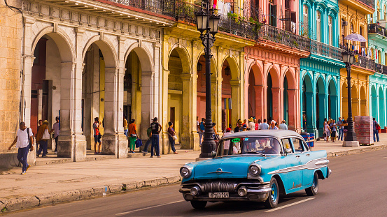 Havana, Cuba on December 22, 2015: A blue oldtimer taxi is driving through Habana Vieja in front of a colorful facade