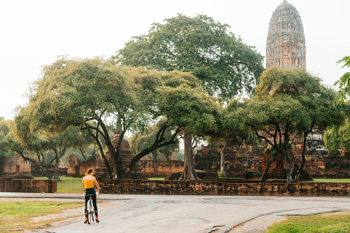 Young Caucasian woman riding bicycle on the background of  the ruins of ancient Buddhist Temples,Thailand