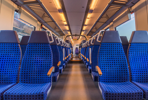 Image with the interior of a german modern train, with no people on the blue chairs