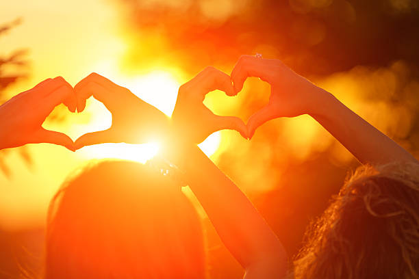 istock Girl-friends making a heart-shape for the sunset. 620734012