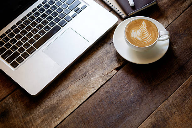 xícara de café de arte latte e laptop na mesa de madeira. - computer coffee laptop business - fotografias e filmes do acervo
