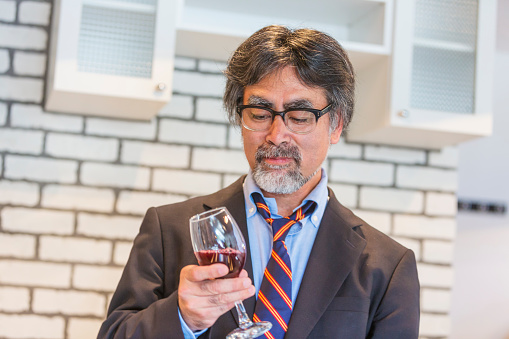 Japanese businessman enjoying a glass of wine while relaxing after work