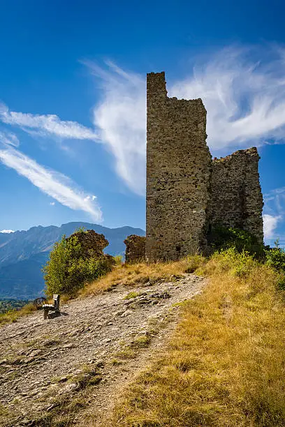 Ruins of Saint-Firmin castle (14th century medieval construction also known as "Le Fort") and a bench at the entrance of Valgaudemar valley in the Hautes-Alpes. Summer in the Southern French Alps. France