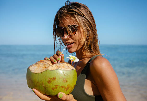 istock Attractive woman drinking coconut water on the beach 620742894