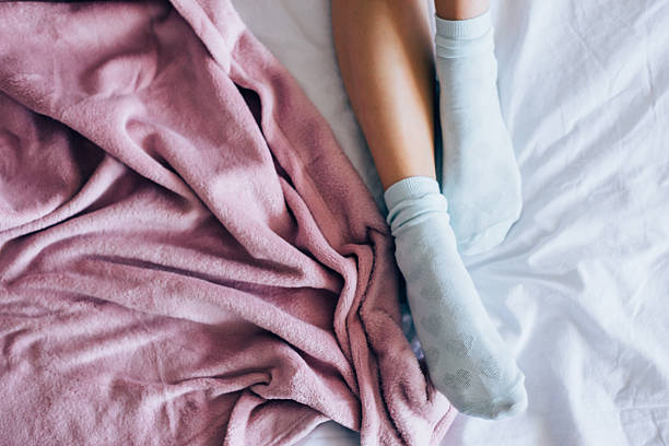 Women leg in bad Legs of girl in warm socks in bad, winter morning at home. pink bed stock pictures, royalty-free photos & images