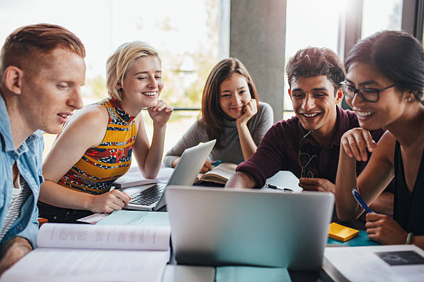 Grupo De Estudiantes Estudiando En La Biblioteca Foto de stock y más banco de imágenes de Estudiante de universidad - Estudiante de universidad, Grupo de personas, Estudiar - iStock