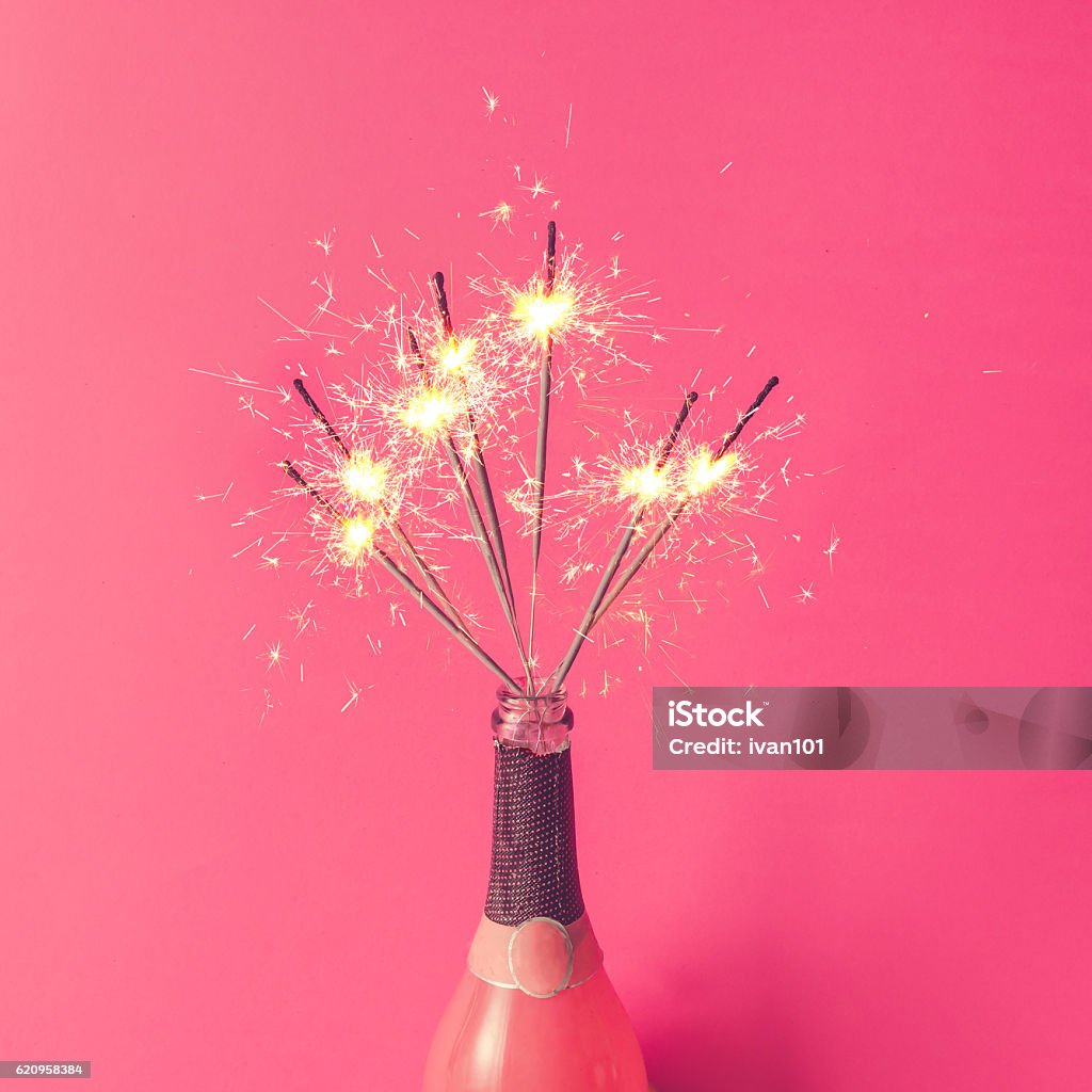 Champagne bottle with sparklers on pink background. Flat lay. Sparkler - Firework Stock Photo