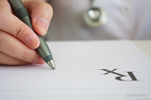 asian female doctor hand writing prescription