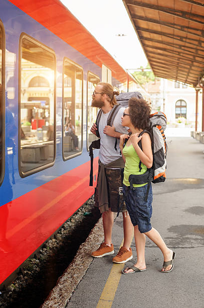 istock Couple of backpacker tourists waiting to board a train 620962812