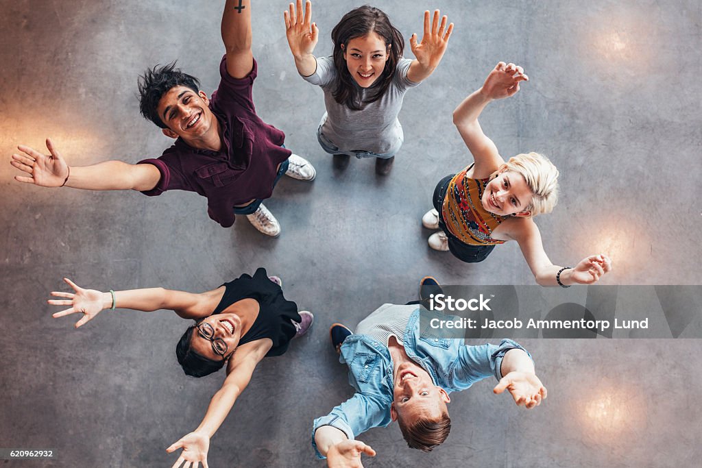 Young students celebrating success Top view of young students standing together looking up at camera with their hands raised in celebration. People Stock Photo