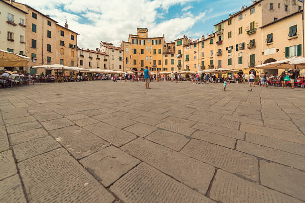 Panorma Piazza Amphitheater lucca Lucca, Italy - August 17, 2016: panorama of the Piazza Anfiteatro in the middle of lucca, Tuscany, Italy. Tourists walk over the place or sitting at one of the many cafes. lucca stock pictures, royalty-free photos & images