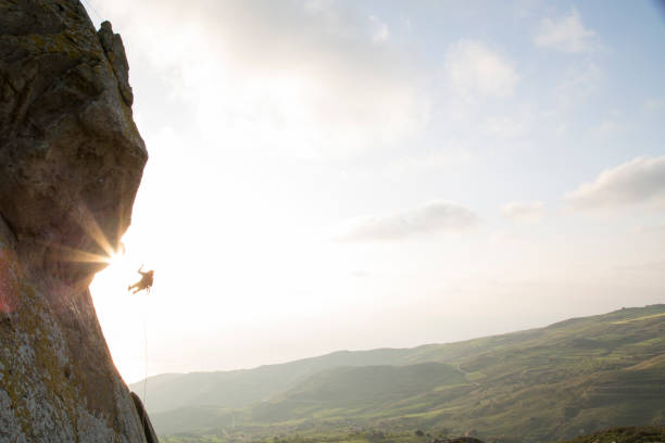 istock Climber carefully descends from overhanging cliff 620969073