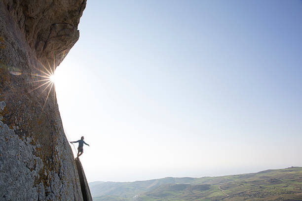 istock Climber extends arm from edge of steep rock cliff 620969077