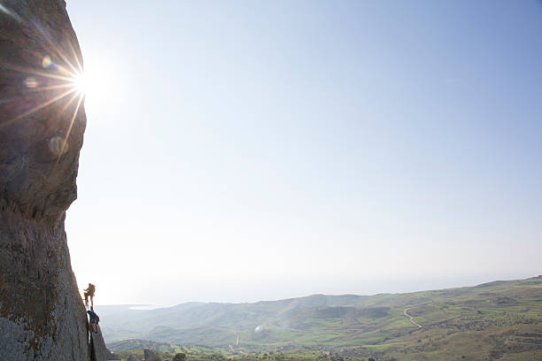 istock Climber belays teammate up steep rock cliff 620969087