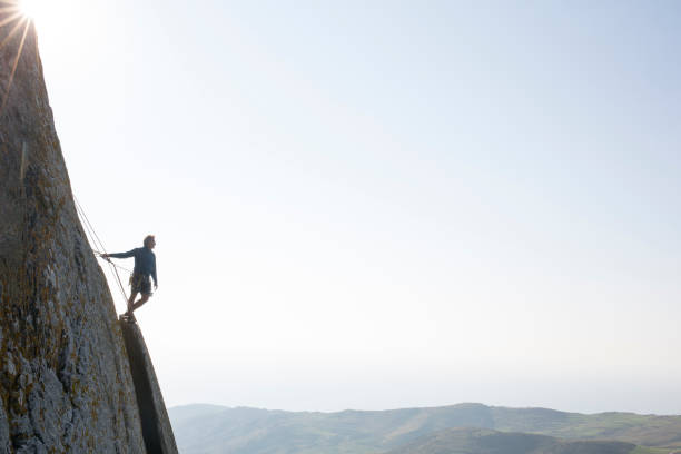 istock Climber looks off from edge of steep rock cliff 620969091