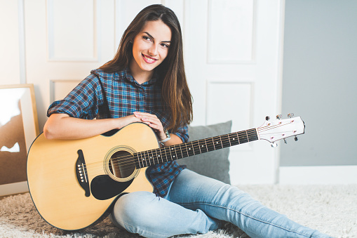 Young woman practicing guitar in living room