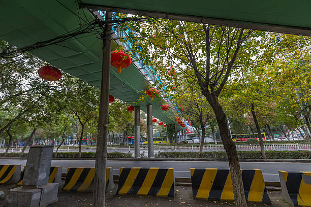 A bridge cross the road, and a lot lanterns hanging on it.