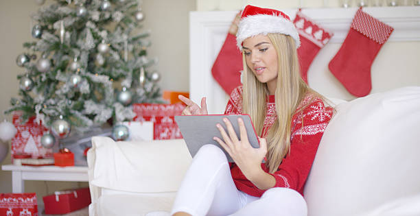 istock Pretty blond young woman sitting on couch with touchpad 620983150