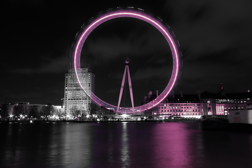 London, England - July 27th 2016: A long exposure of the London Eye lit up in pink from the northbank of the Thames
