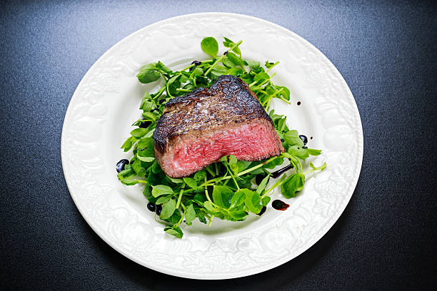 istock Beef steak sliced Mignon with salad. Served on white plate 620985942