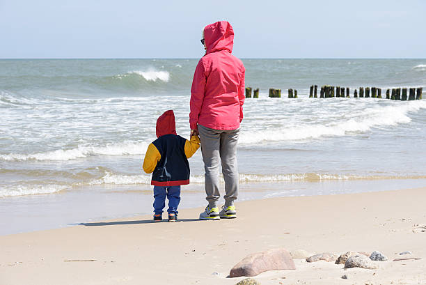 istock Mother stands with her son on a beach 620990638