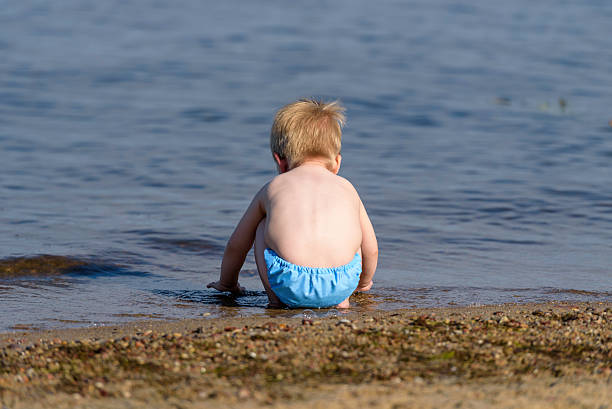 istock Little boy playing with water on a beach 620990950
