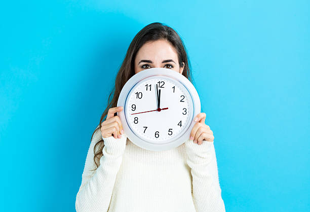 istock Woman holding clock showing nearly 12 620991234