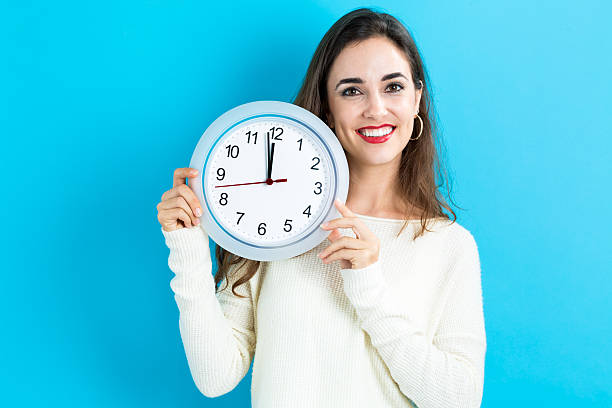 istock Woman holding clock showing nearly 12 620991252