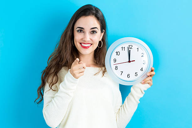 istock Woman holding clock showing nearly 12 620991268