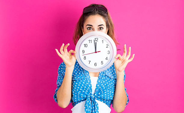 istock Woman holding clock showing nearly 12 620991498