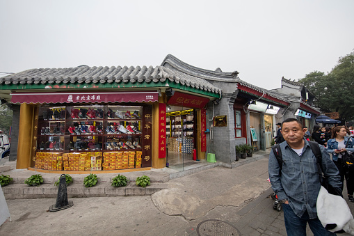Beijing, China - October 18, 2016: Nanluoguxiang(Hutong), Beijing, China. Nanluoguxiang, a tourist-friendly hutong alley with many shops and eateries located in the Dongcheng district. Tourists are walking on the street and a gentleman on the front.