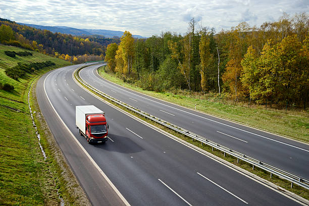 autopista con un pequeño camión rojo en el paisaje de otoño. - riding autumn meadow land fotografías e imágenes de stock