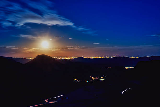 This Hunter's Moon was photographed from a mountain in Rocky Mountain National Park.  The view is looking east over the valley towards Loveland, Colorado as the full moon rises.  Traffic lights and lights from Estates Park can be seen in the shadows of the mountains.