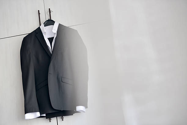 istock Black suit hanged to a wood closet in natural light 620994068