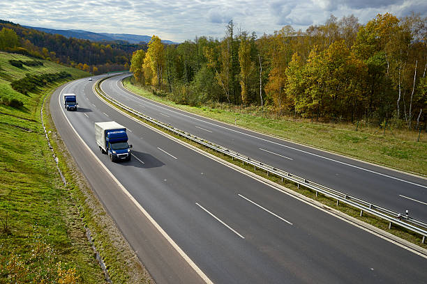 istock Asphalt expressway with blue small trucks in the autumn landscape. 620994254