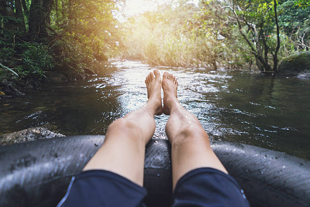 hombre flotando por un canal en un tubo de explosión - flotador fotografías e imágenes de stock