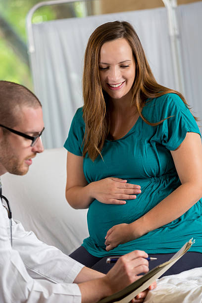 istock Ob/gyn reviews a patient's chart during prenatal exam 621099938
