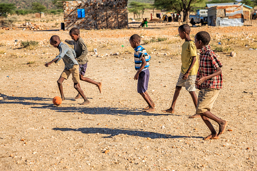 Barefoot African children  from Samburu tribe playing football in the village, East Africa, Kenya, East Africa. Samburu tribe is one of the biggest tribes of north-central Kenya, and they are related to the Maasai.