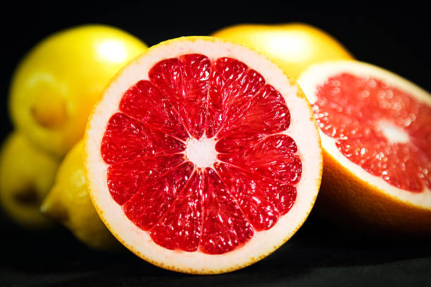 背景にカットグレープフルーツとレモンのクローズアップ - lemon textured peel portion ストックフォトと画像