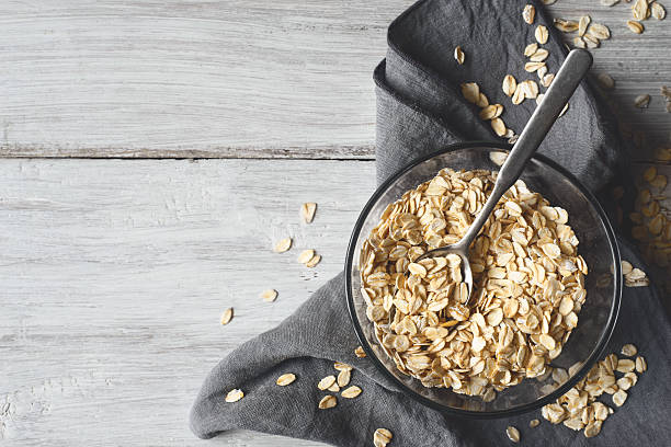 copos de avena en un tazón de vidrio en la mesa de madera - wheat whole wheat close up cereal plant fotografías e imágenes de stock