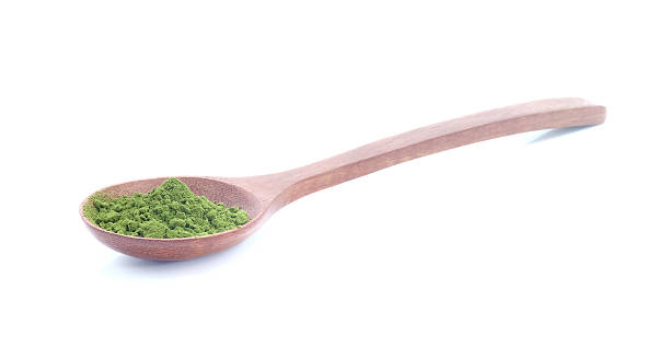 istock Green tea powder in woodden spoon on white background. 621115878