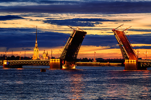 View through the opened bascule Palace Bridge and Neva river to Peter and Paul Fortress at white night time, St Petersburg, Russia