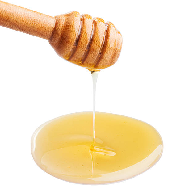 istock Honey dripping from a wooden dipper on isolate white background. 621117334
