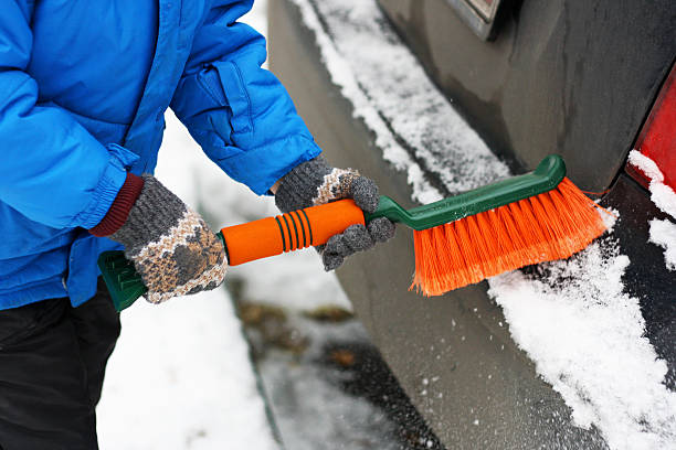 istock The child cleans the car from snow. 621118412