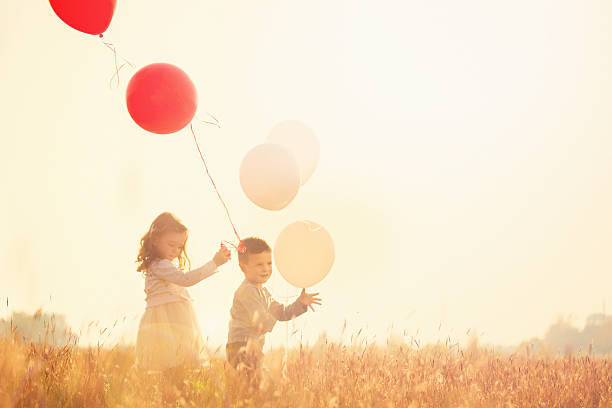 istock Brother and sister holding balloons and running 621121114