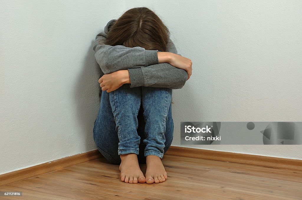 Lonely girl Lonely girl crying in the corner Child Abuse Stock Photo